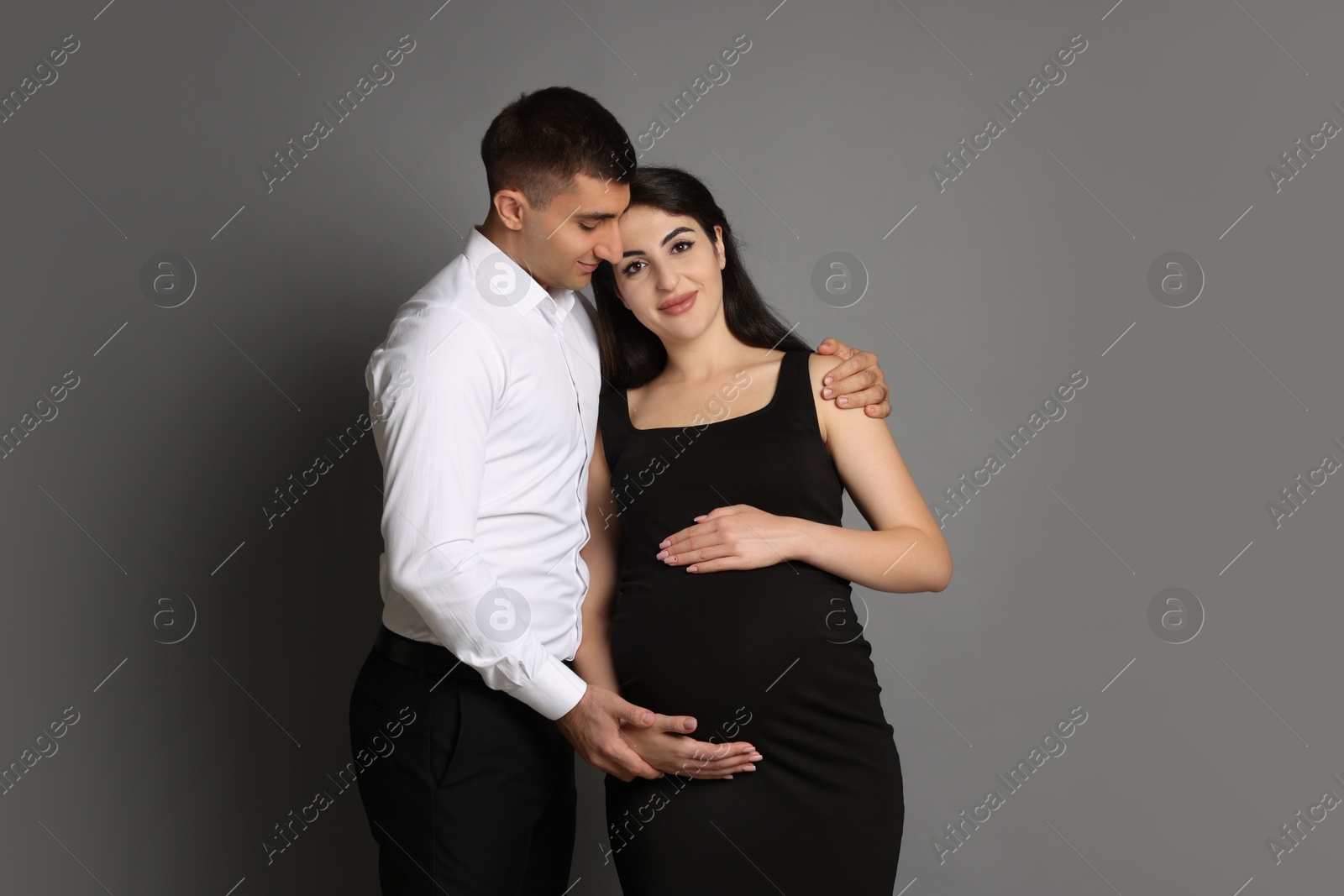 Photo of Beautiful pregnant woman with her husband on grey background