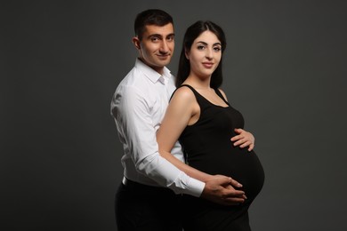 Photo of Beautiful pregnant woman with her husband on grey background