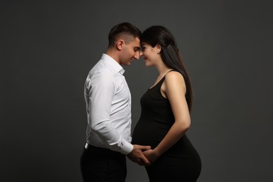 Photo of Beautiful pregnant woman with her husband on grey background