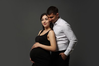 Photo of Beautiful pregnant woman with her husband on grey background