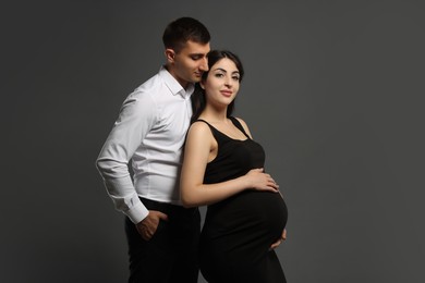 Photo of Beautiful pregnant woman with her husband on grey background