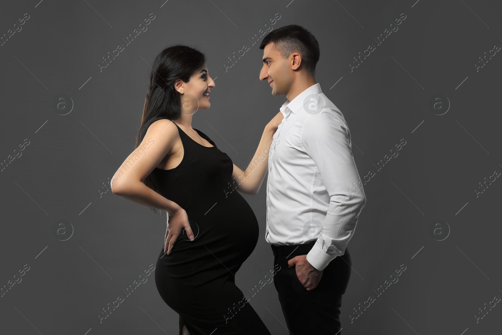 Photo of Beautiful pregnant woman with her husband on grey background