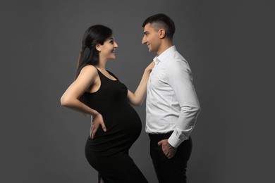 Photo of Beautiful pregnant woman with her husband on grey background