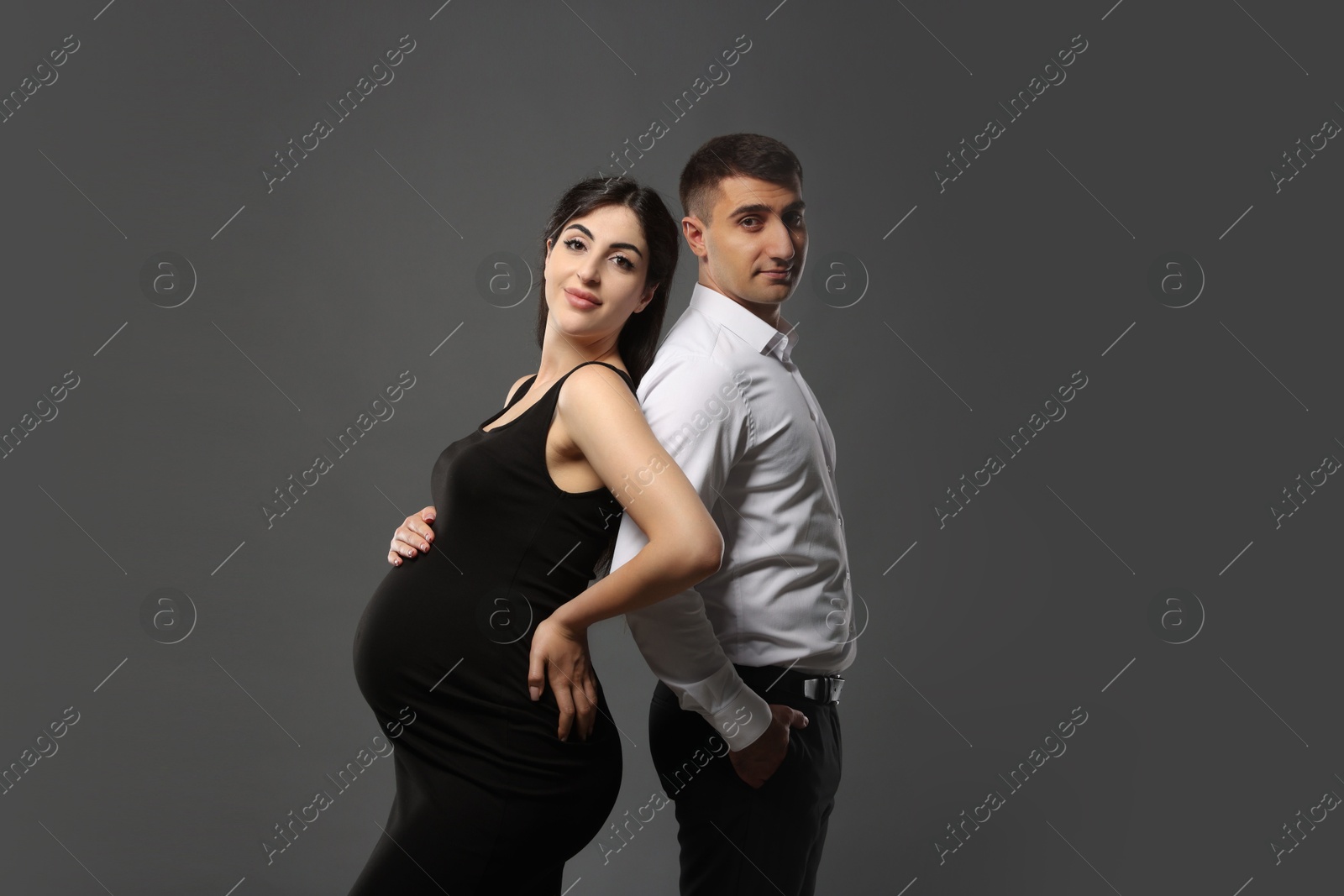 Photo of Beautiful pregnant woman with her husband on grey background