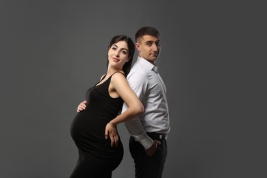 Photo of Beautiful pregnant woman with her husband on grey background