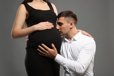 Photo of Pregnant woman with her husband on grey background, closeup