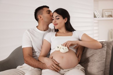 Photo of Beautiful pregnant woman with baby booties and her husband at home