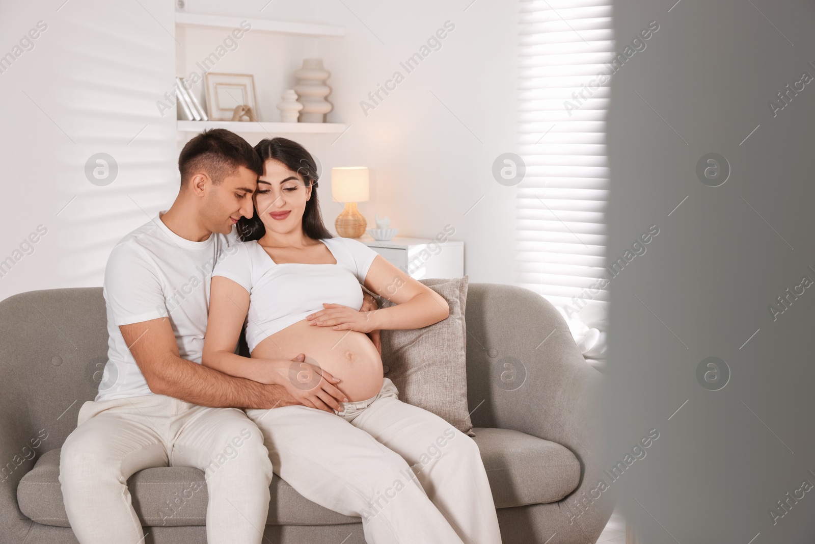 Photo of Beautiful pregnant woman spending time with her husband at home, space for text