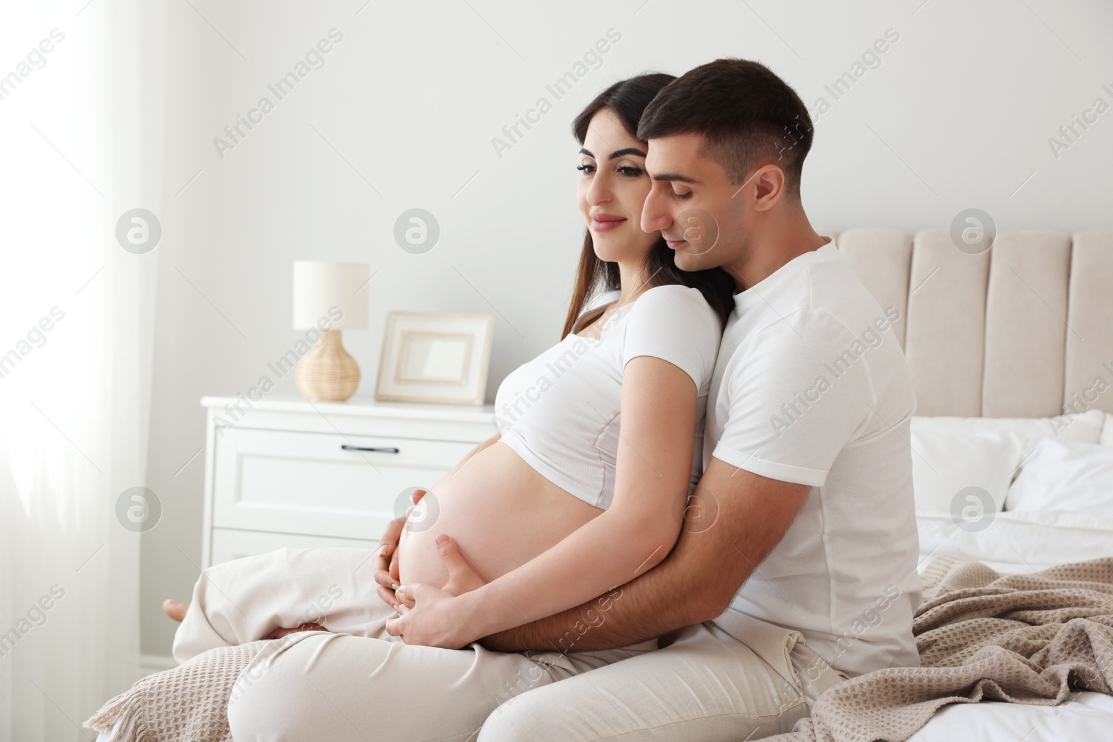 Photo of Beautiful pregnant woman spending time with her husband in bedroom