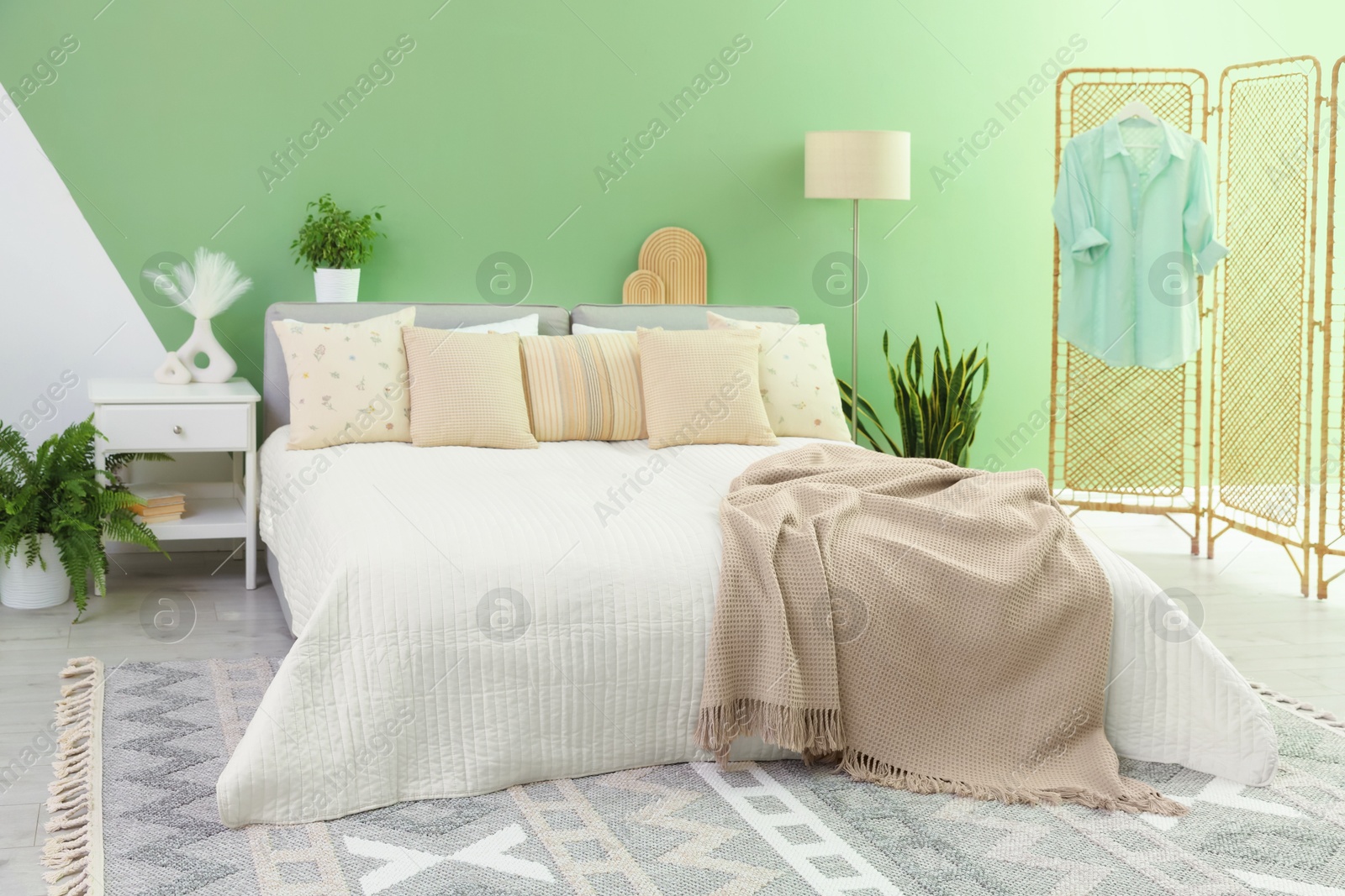 Photo of Stylish bedroom interior with large bed, houseplants and decorative elements