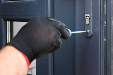 Photo of Repairman installing new door with screwdriver indoors, closeup