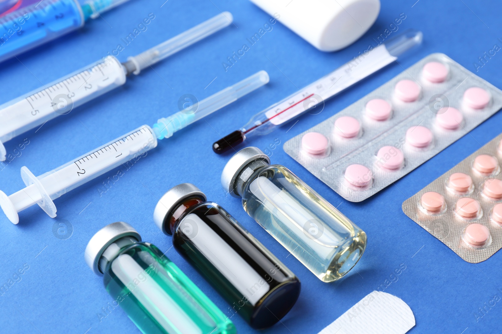 Photo of Pharmacist concept. Vials, syringes and pills on blue background, closeup