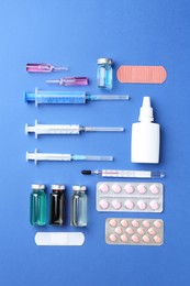 Pharmacist concept. Flat lay composition with vials, syringes and pills on blue background