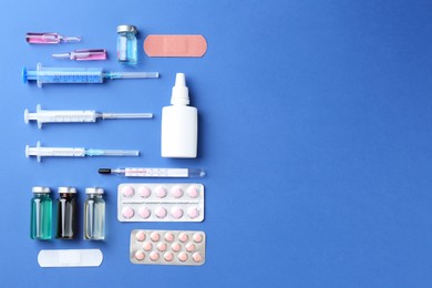 Pharmacist concept. Flat lay composition with vials, syringes and pills on blue background, space for text