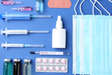 Pharmacist concept. Flat lay composition with vials, medical masks, syringes and pills on blue background