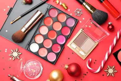 Flat lay composition with makeup products and Christmas decor on red background