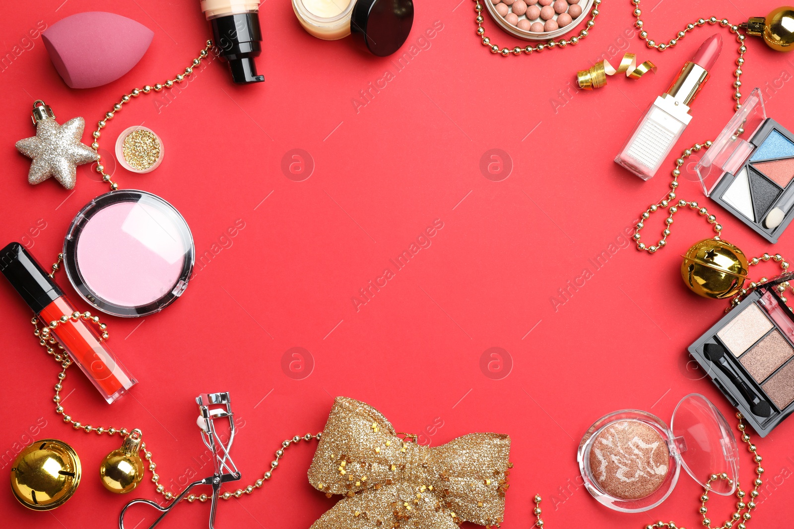 Photo of Frame of makeup products and Christmas decor on red background, flat lay. Space for text