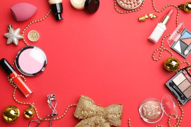 Photo of Frame of makeup products and Christmas decor on red background, flat lay. Space for text