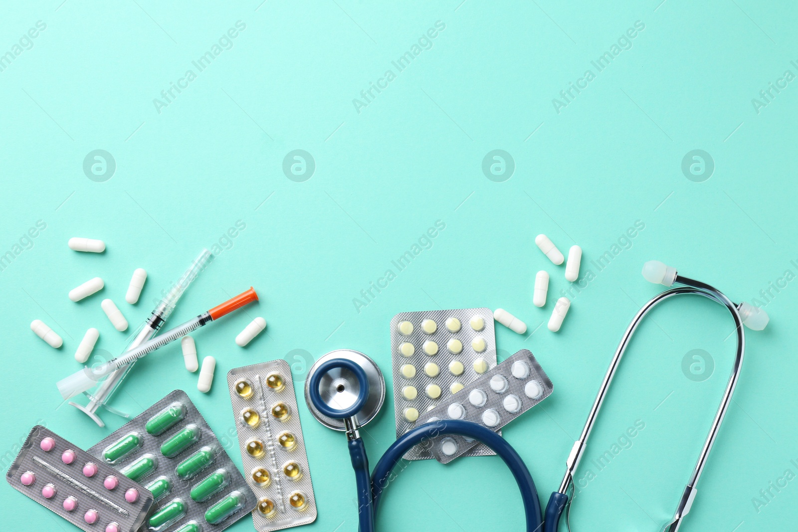 Photo of Pharmacist. Many different pills, stethoscope and syringes on light blue background, flat lay