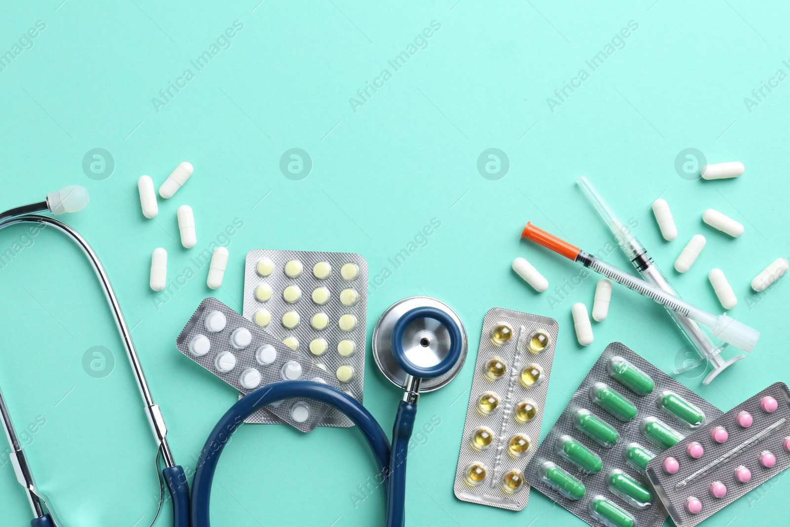 Photo of Pharmacist. Many different pills, stethoscope and syringes on light blue background, flat lay