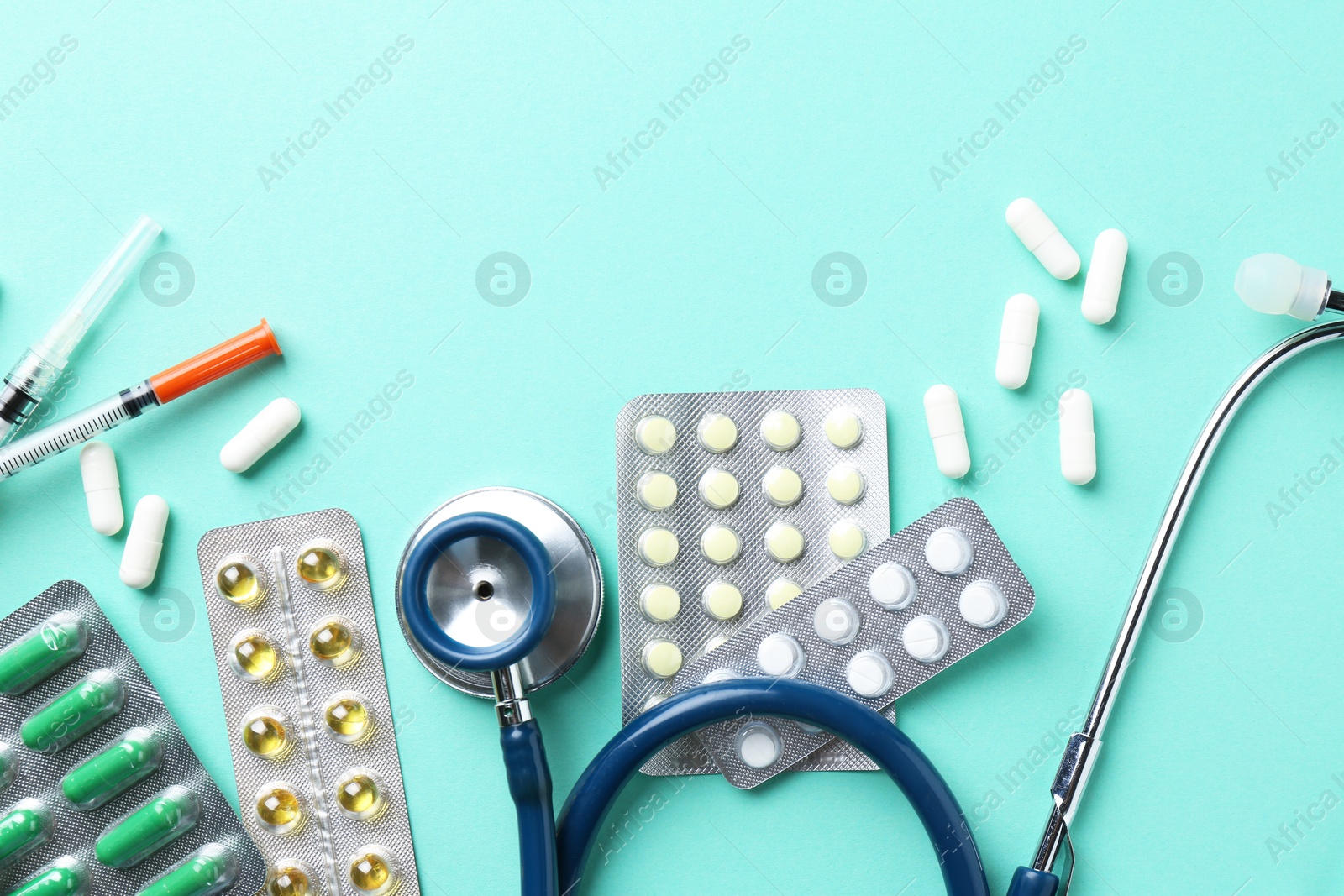 Photo of Pharmacist. Many different pills, stethoscope and syringes on light blue background, flat lay