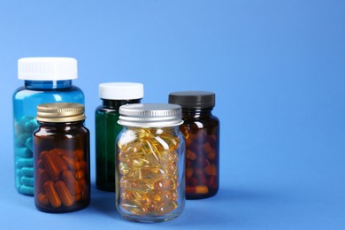 Photo of Pharmacist. Different pills in plastic bottles on blue background, space for text