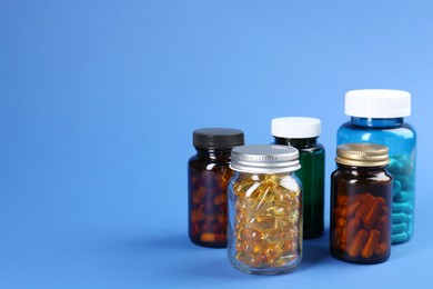 Photo of Pharmacist. Different pills in plastic bottles on blue background, space for text