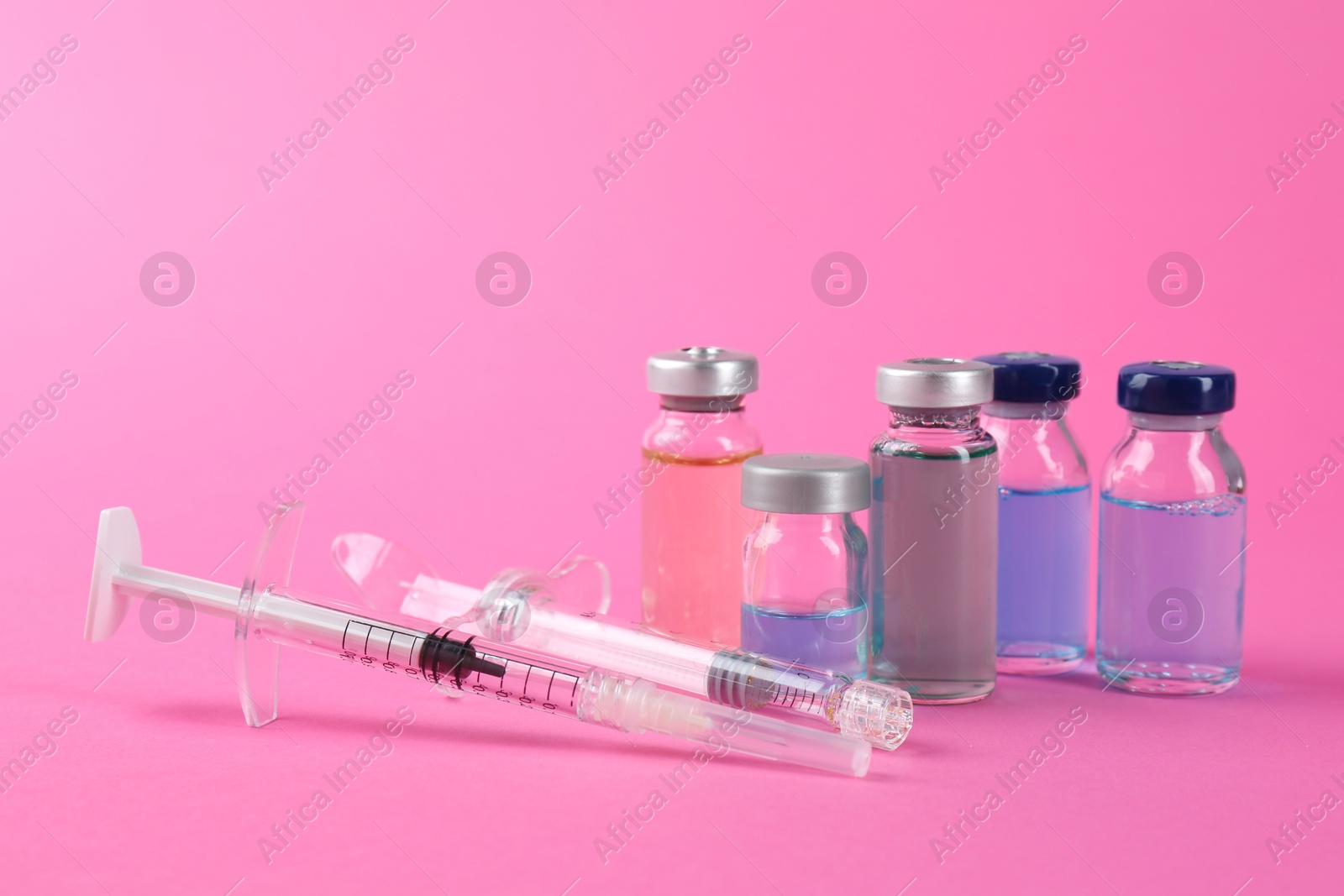 Photo of Pharmacist. Glass vial with medication and syringes on pink background