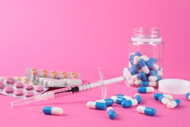 Pharmacist. Many different pills and syringe on pink background