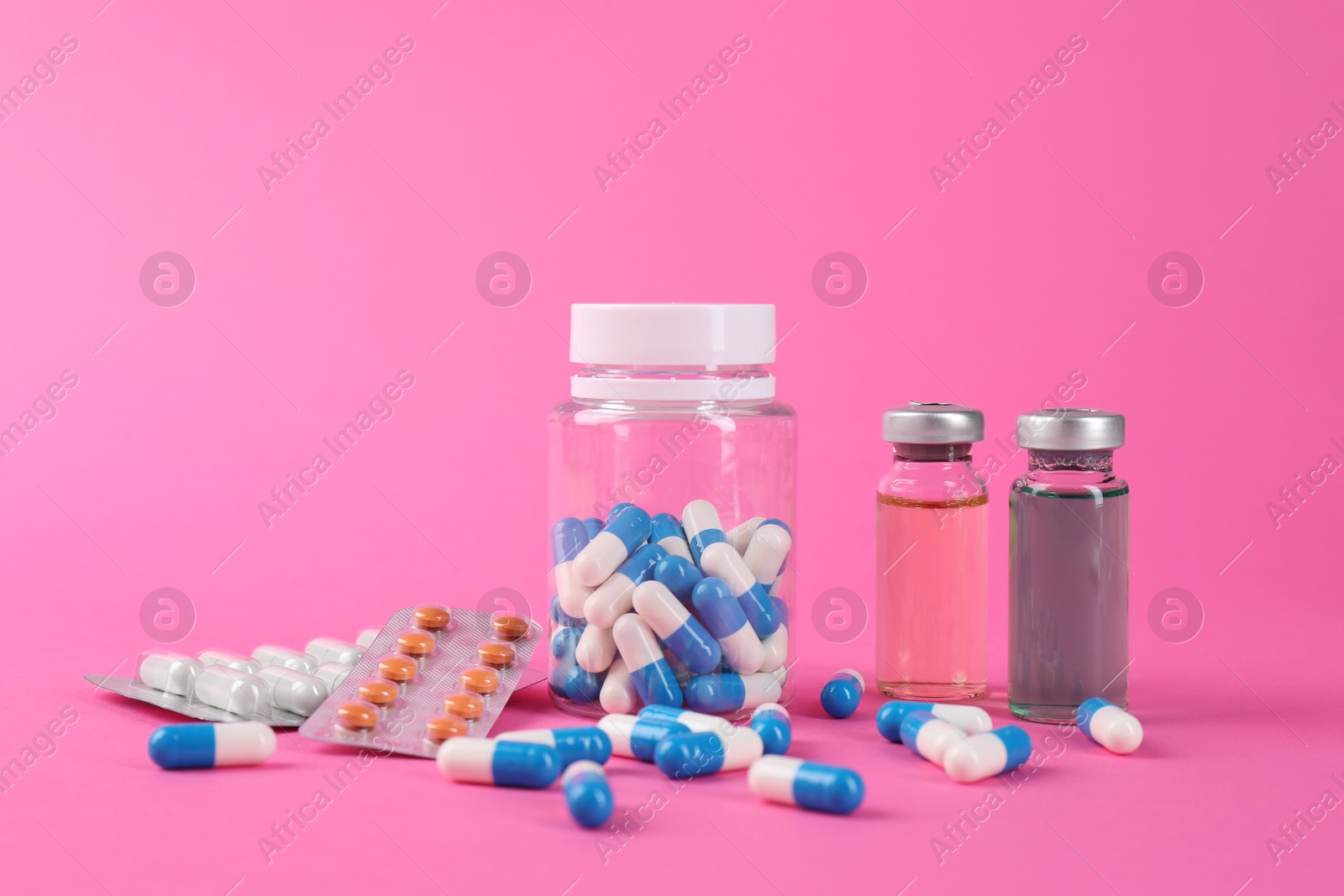 Photo of Pharmacist. Many different pills and vials with medication on pink background