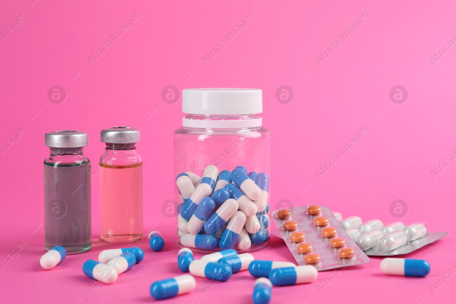 Photo of Pharmacist. Many different pills and vials with medication on pink background