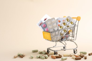 Pharmacist. Many different pills in small shopping cart on beige background