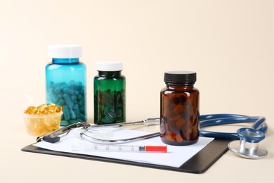 Pharmacist. Pills in plastic bottles, clipboard, syringe and stethoscope on beige background