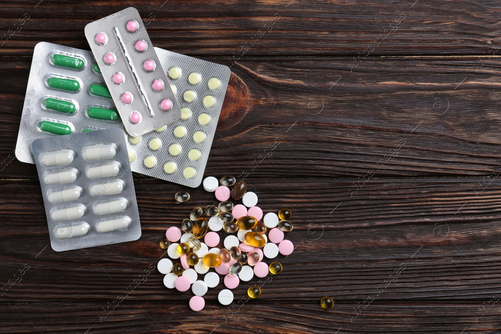 Photo of Pharmacist. Many different pills on wooden table, flat lay. Space for text