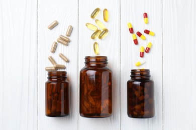 Photo of Pharmacist. Many different pills and overturned bottles on white wooden table, flat lay