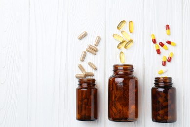 Photo of Pharmacist. Many different pills and overturned bottles on white wooden table, flat lay. Space for text