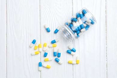 Photo of Pharmacist. Many different pills and overturned bottle on white wooden table, top view