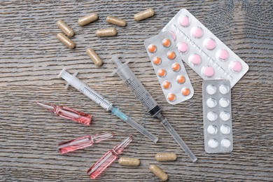 Photo of Pharmacist. Many different pills, syringes and ampoules on wooden table, flat lay