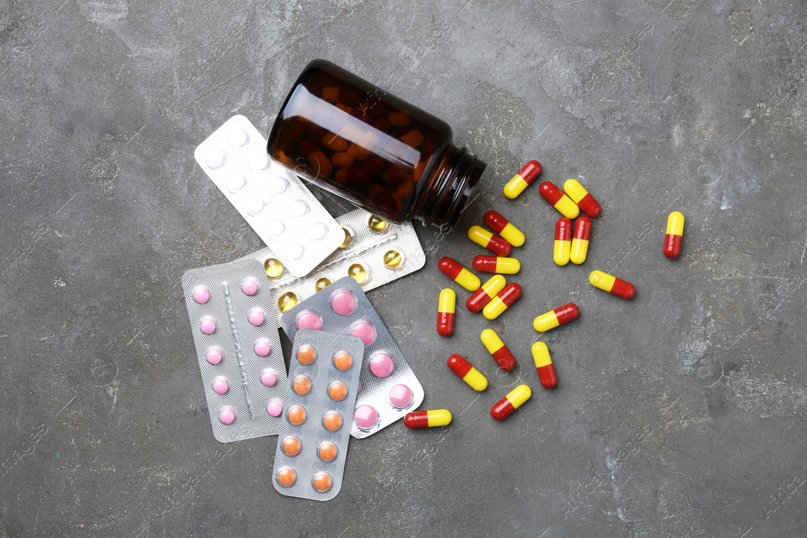 Photo of Pharmacist. Many different pills and overturned bottle on grey table, flat lay