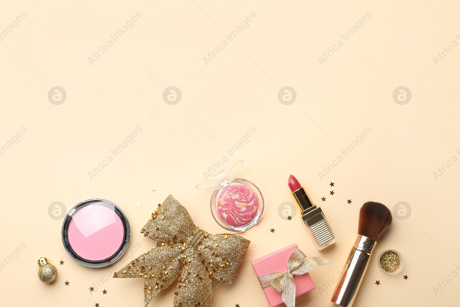 Photo of Flat lay composition with makeup products and Christmas decor on beige background. Space for text