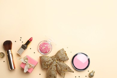 Photo of Flat lay composition with makeup products and Christmas decor on beige background. Space for text