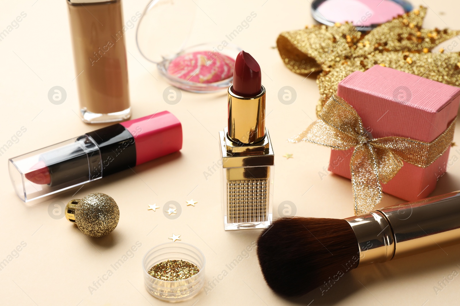 Photo of Different makeup products and Christmas decor on beige background, closeup