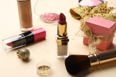 Photo of Different makeup products and Christmas decor on beige background, closeup