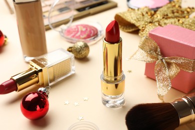 Different makeup products and Christmas decor on beige background, closeup