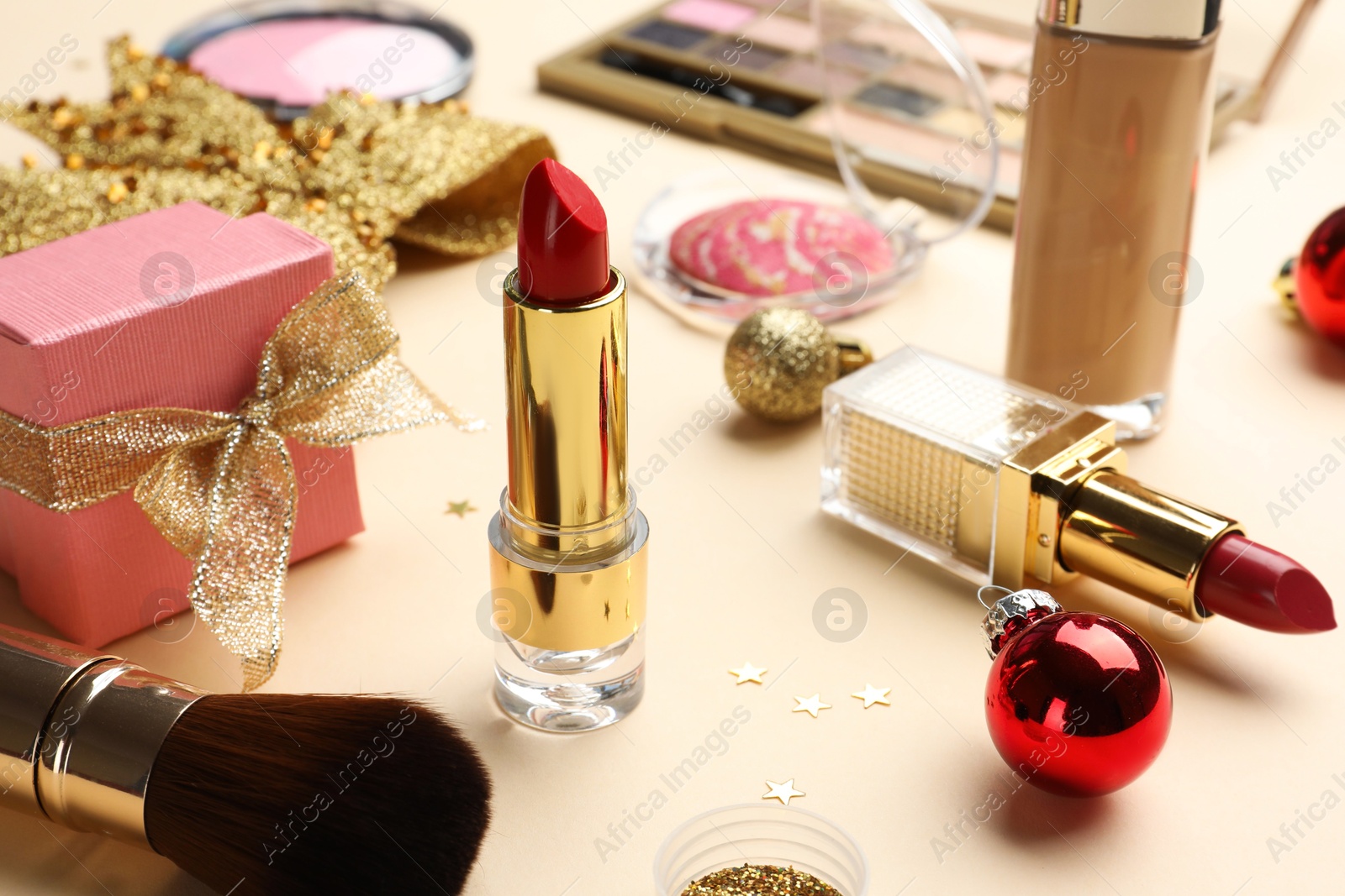 Photo of Different makeup products and Christmas decor on beige background, closeup