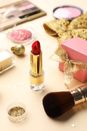 Different makeup products and Christmas decor on beige background, closeup