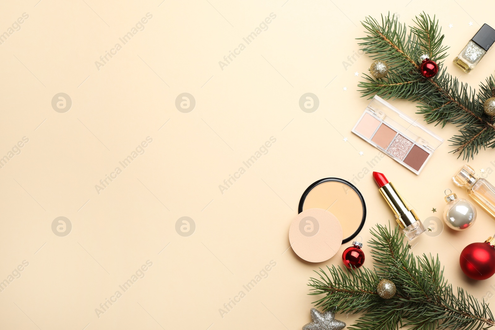 Photo of Flat lay composition with makeup products and Christmas decor on beige background. Space for text