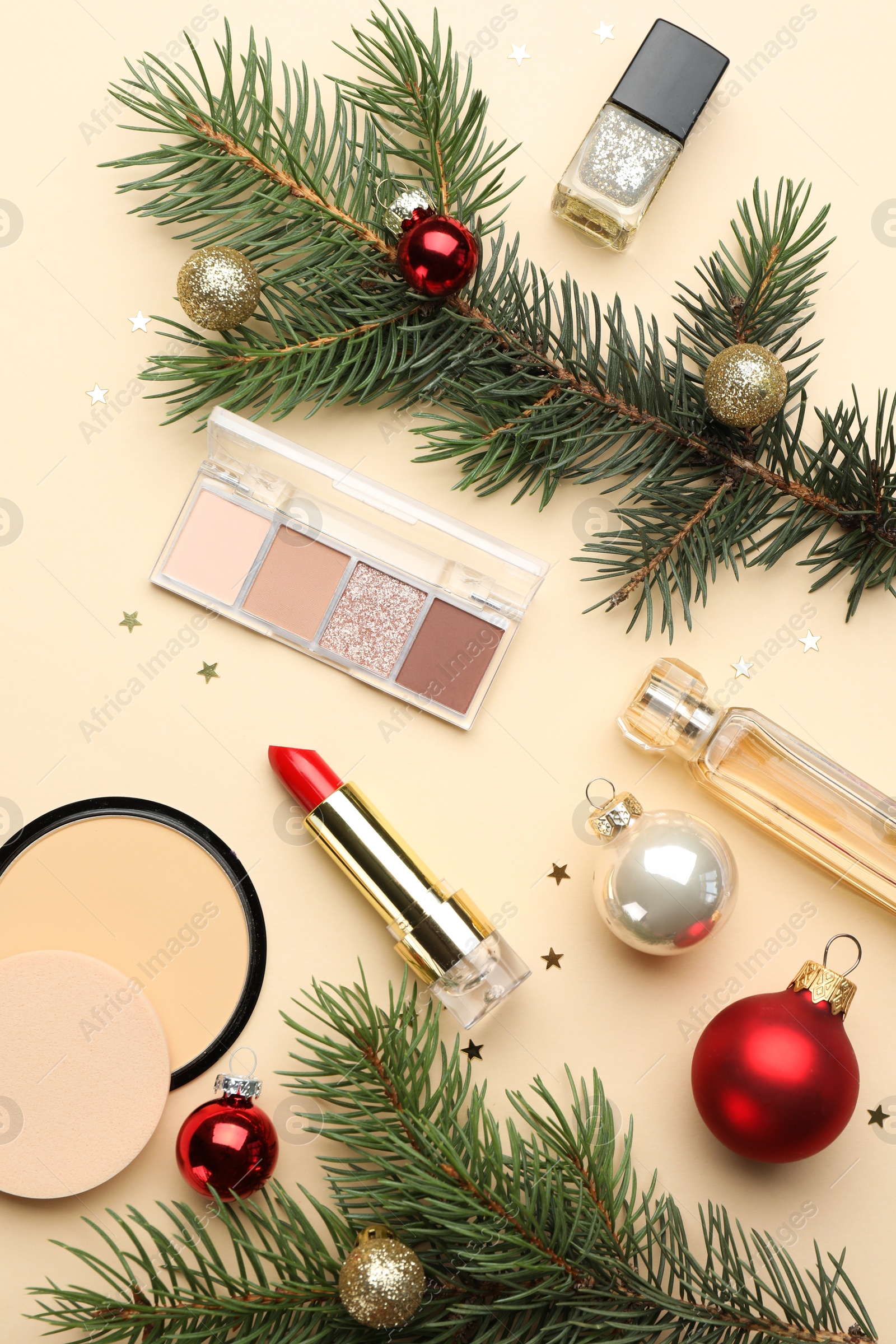 Photo of Flat lay composition with makeup products and Christmas decor on beige background