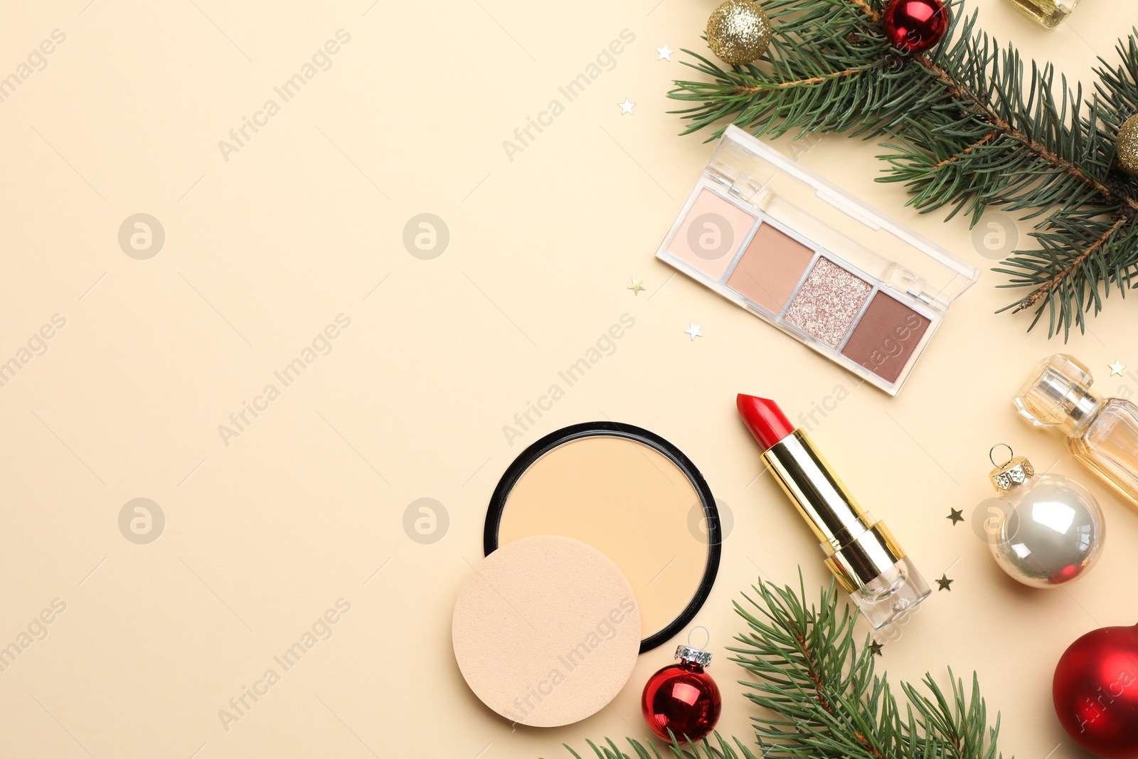 Photo of Flat lay composition with makeup products and Christmas decor on beige background. Space for text