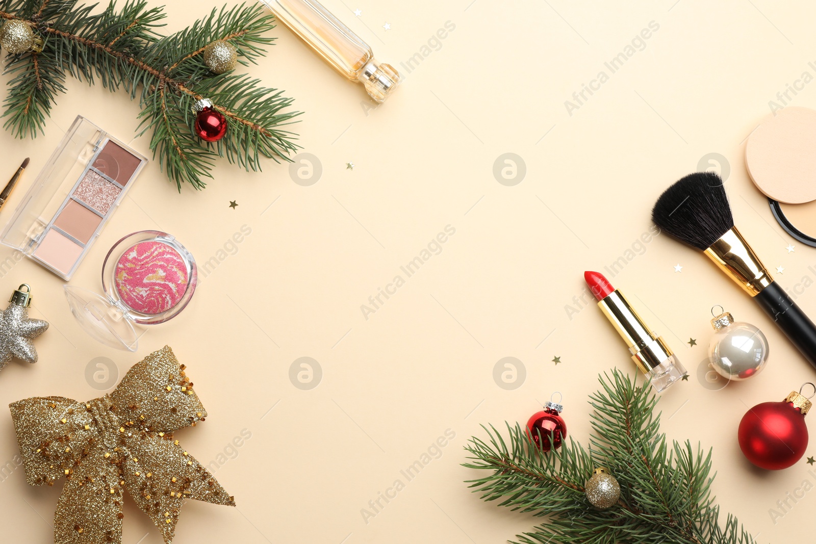 Photo of Frame made of makeup products and Christmas decor on beige background, flat lay. Space for text